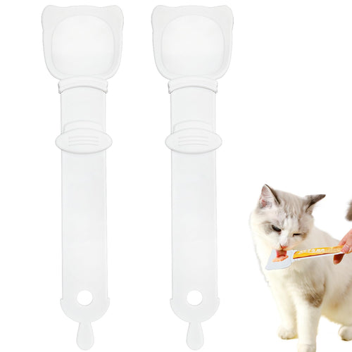 Two clear silicone cat treat squeeze spoons beside a white cat licking a treat from one of them.